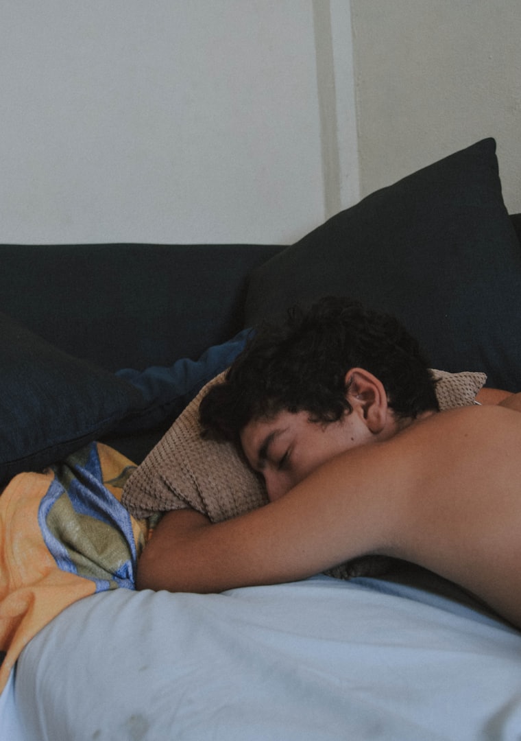 Someone asleep in bed, face to the pillow, early light.